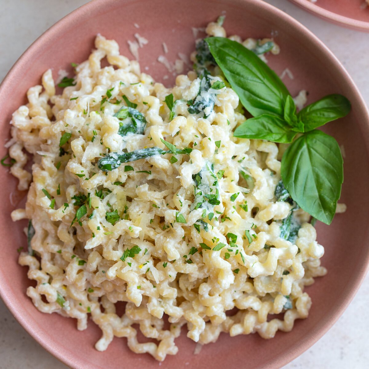 A bowl of creamy ricotta pasta topped with fresh herbs and parmesan cheese