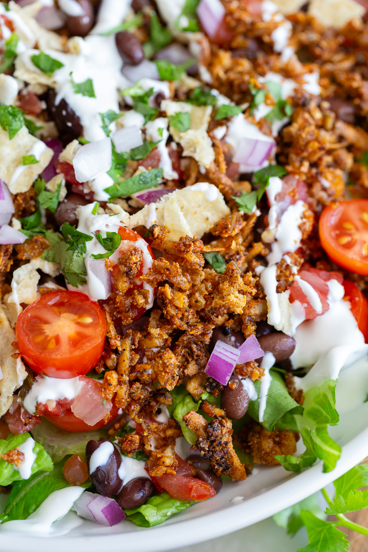 taco tofu rice bowls that is a large bowl of lettuce topped with rice, cherry tomatoes, crispy tofu taco meat, and drizzled with sour cream