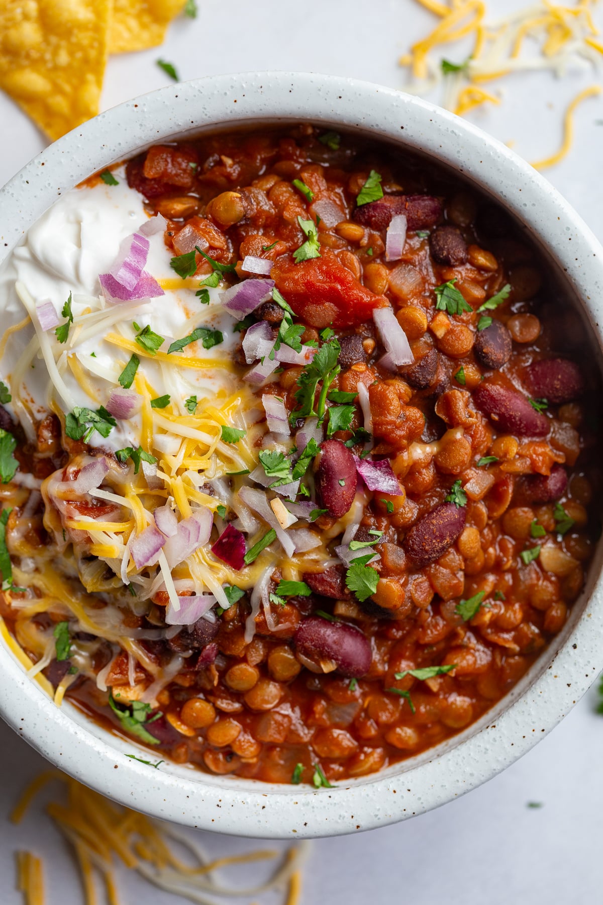 big bowl of lentil chili topped with sour cream and shredded cheese