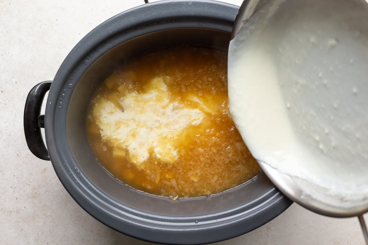 roux being poured into a crockpot to make potato soup