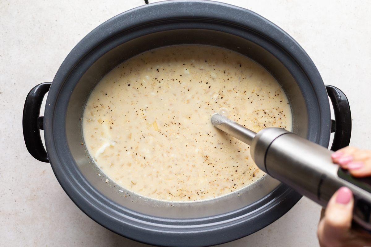 immersion blender stuck into a slow cooker to blend up potato soup