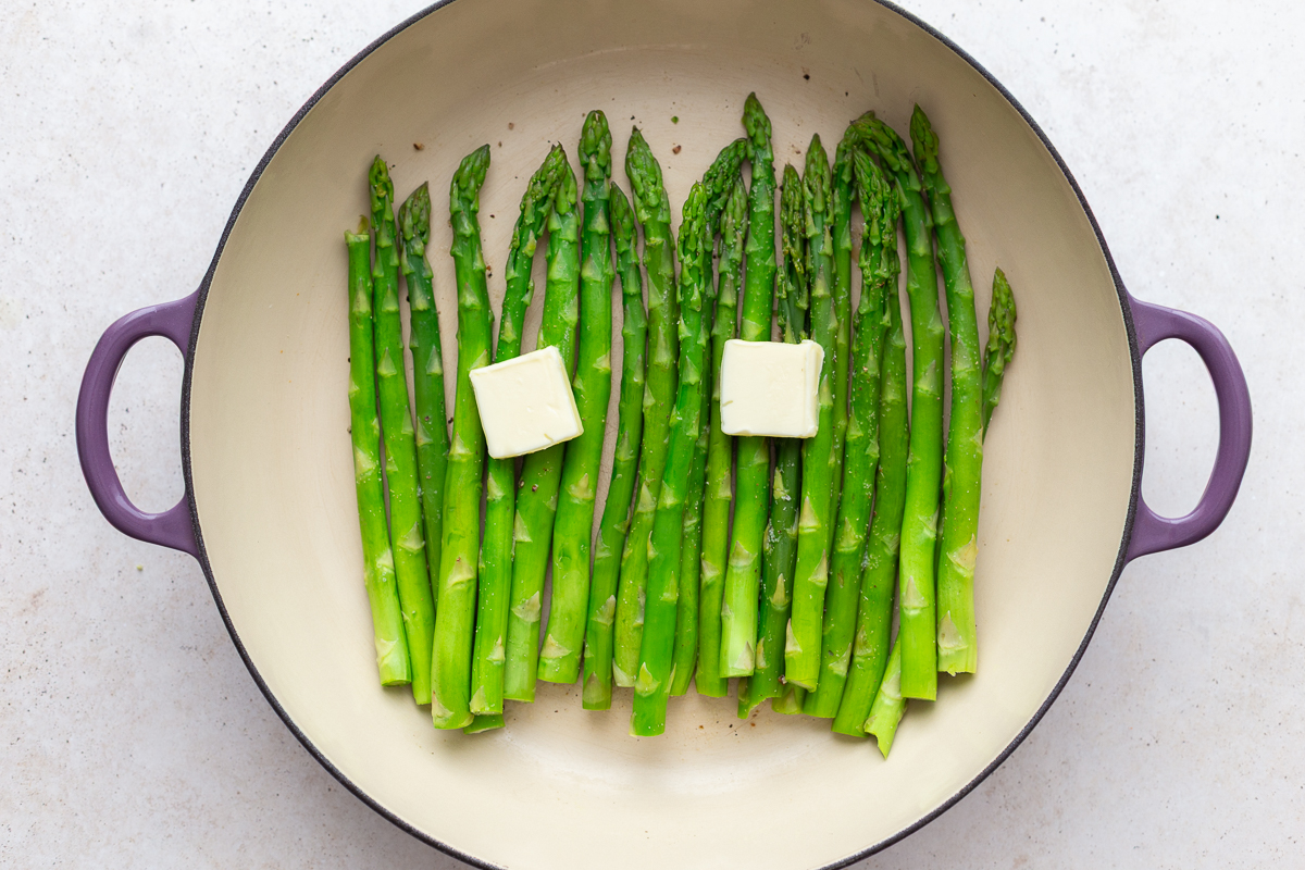 streamed asparagus in a large skillet with pads of butter on top