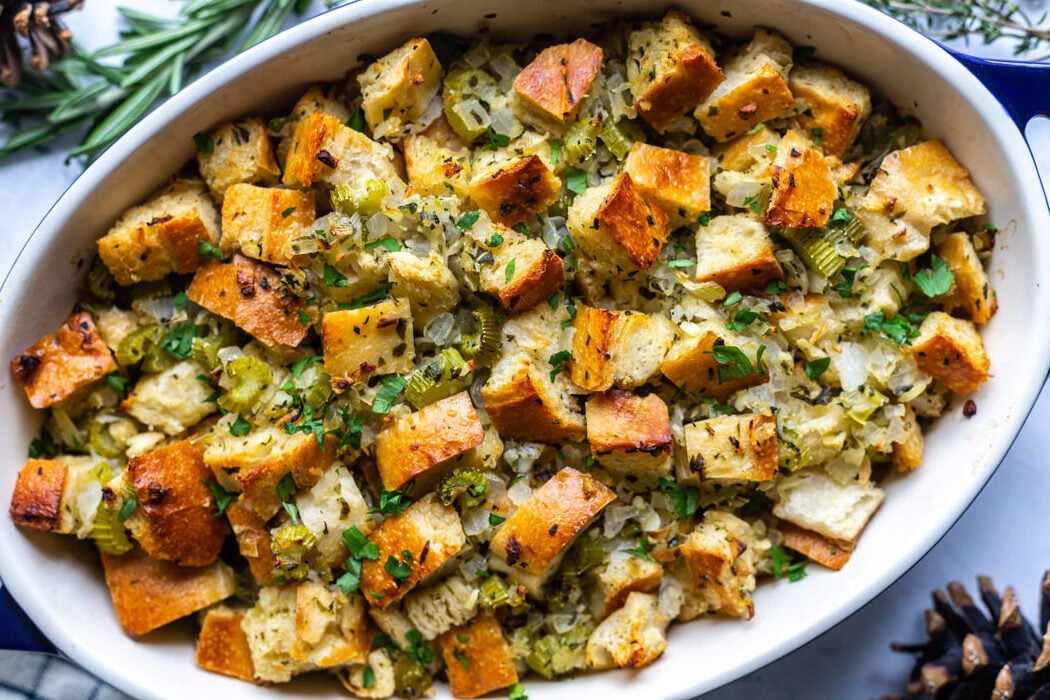 casserole dish filled with a simple vegan stuffing recipe topped with fresh herbs