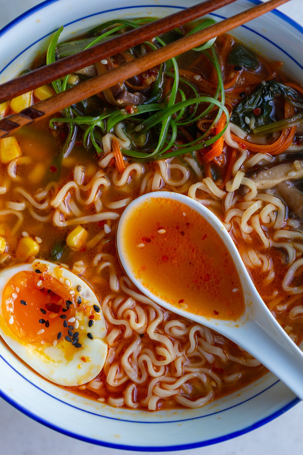 easy homemade ramen in a large ramen bowl. the ramen is topped with a soft boiled egg, green onions, corn, and sesame seeds