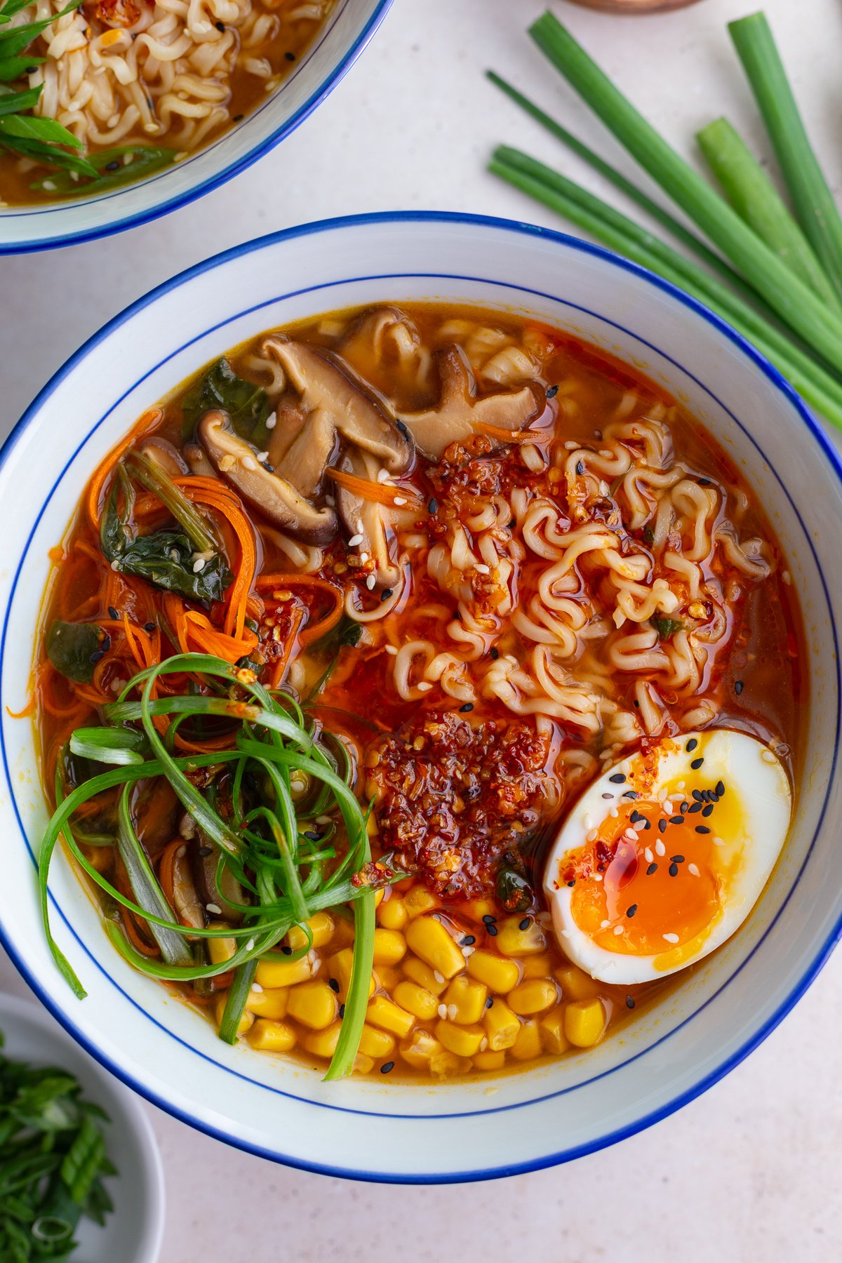 easy homemade ramen in a large ramen bowl. the ramen is topped with a soft boiled egg, green onions, corn, and sesame seeds