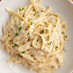 large bowl of fettuccini alfredo homemade topped with fresh parsley