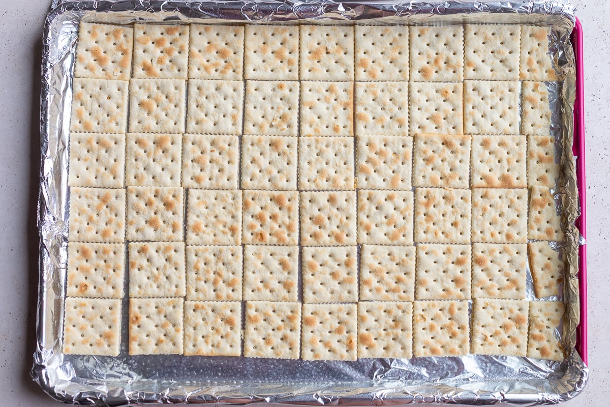 saltine crackers lined up on a baking tray to make christmas crack