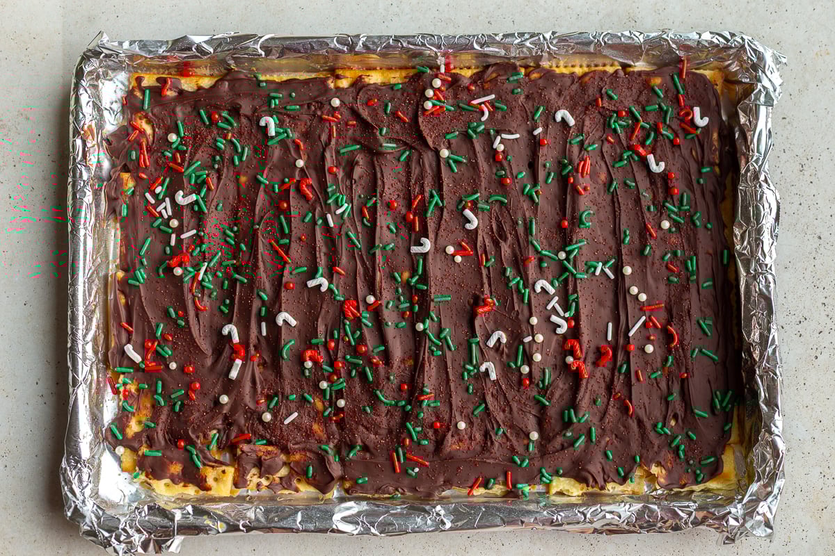 christmas crack candy on a baking tray and topped with christmas sprinkles