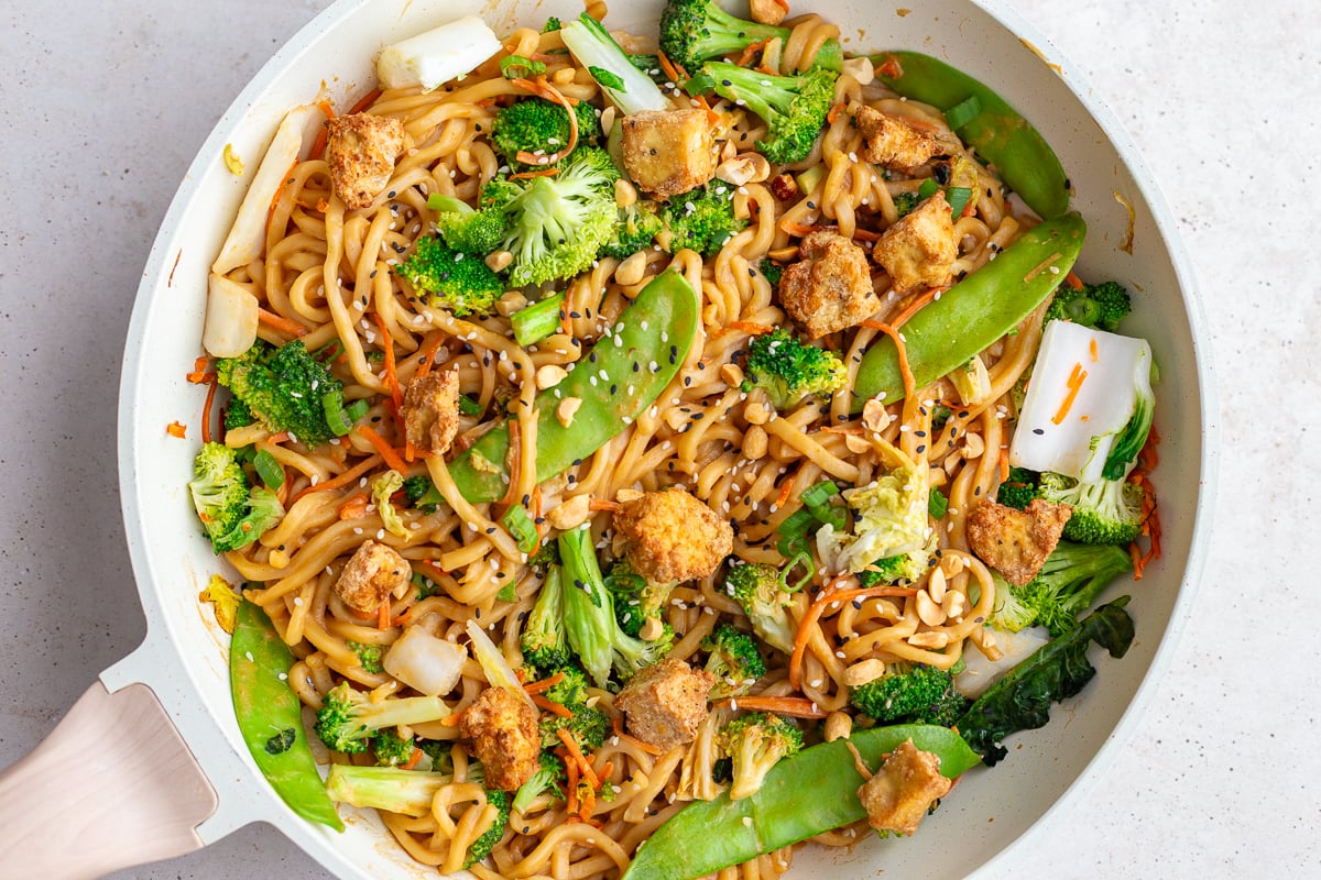peanut tofu noodles in a skillet with veggies and tofu chunks