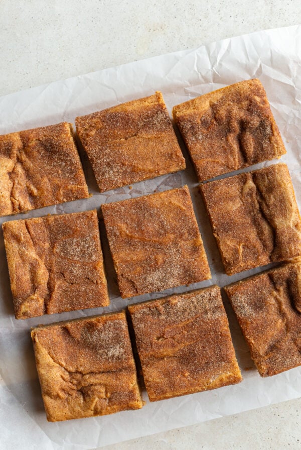 9 snickerdoodle blondies bars cut on a piece of parchment paper