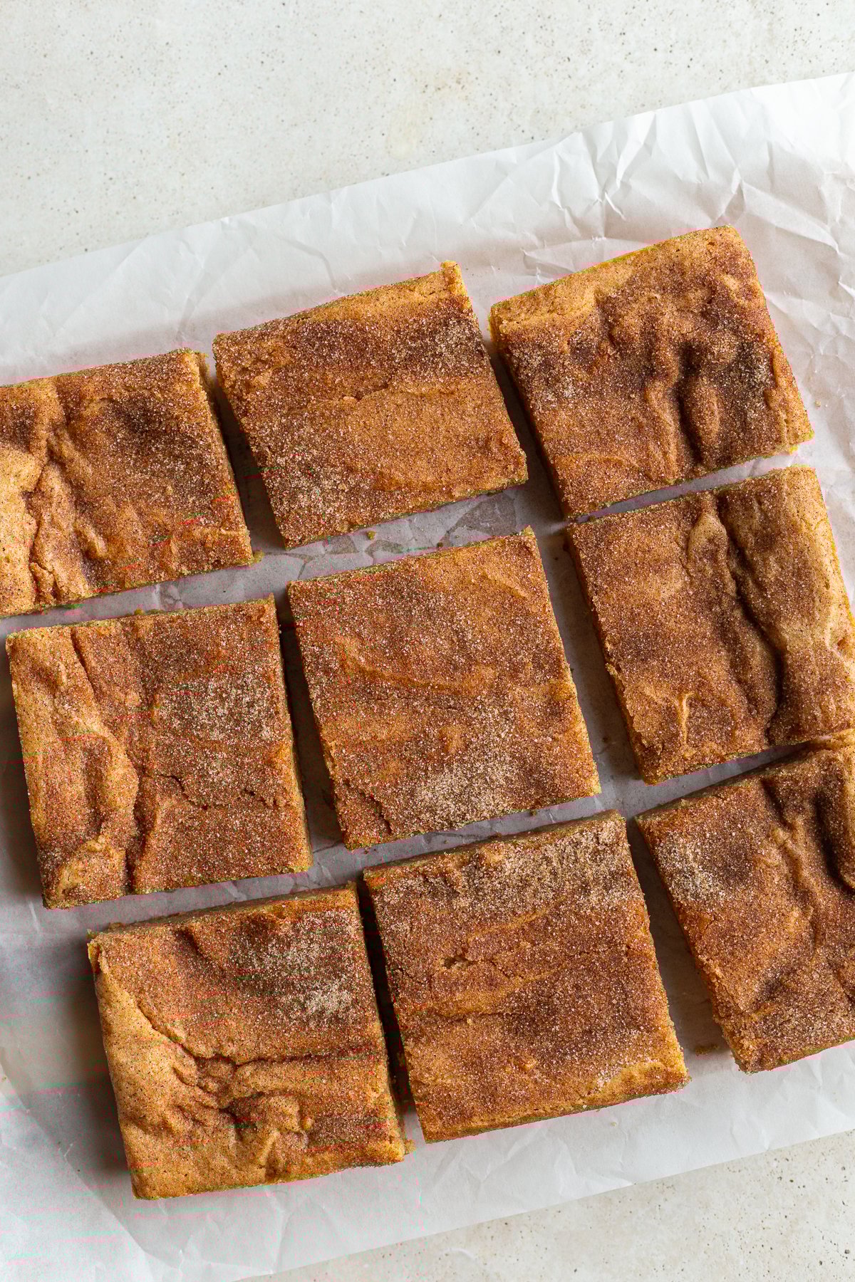 9 snickerdoodle blondies bars cut on a piece of parchment paper