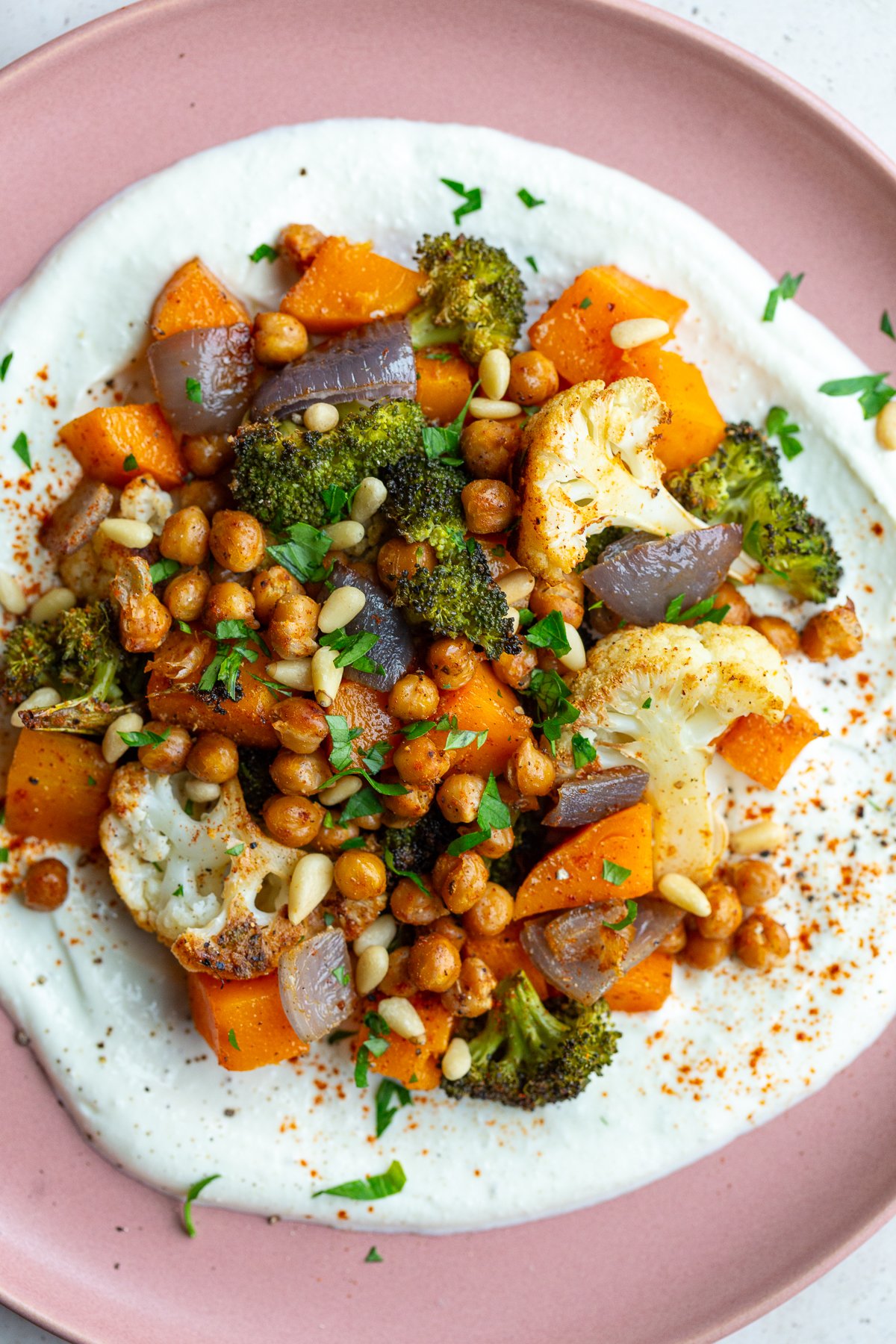 pink plate with whipped feta and roasted veggies on it