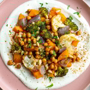 pink plate with whipped feta and roasted veggies on it