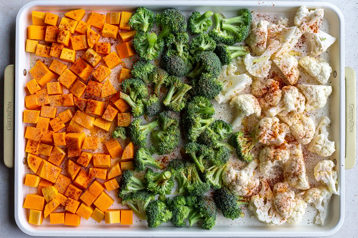 butternut squash, broccoli and cauliflower florets lined up on a baking tray and sprinkled with spices