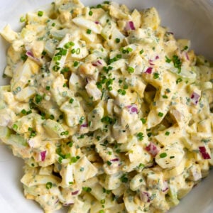 large bowl filled with homemade egg salad topped with chives