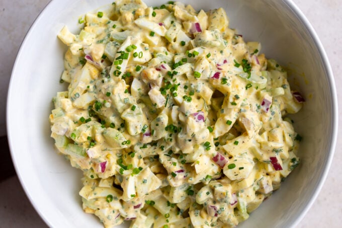 large bowl filled with homemade egg salad topped with chives