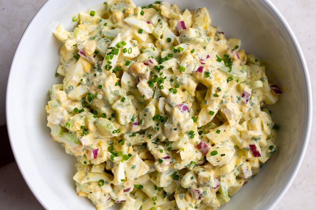 large bowl filled with homemade egg salad topped with chives
