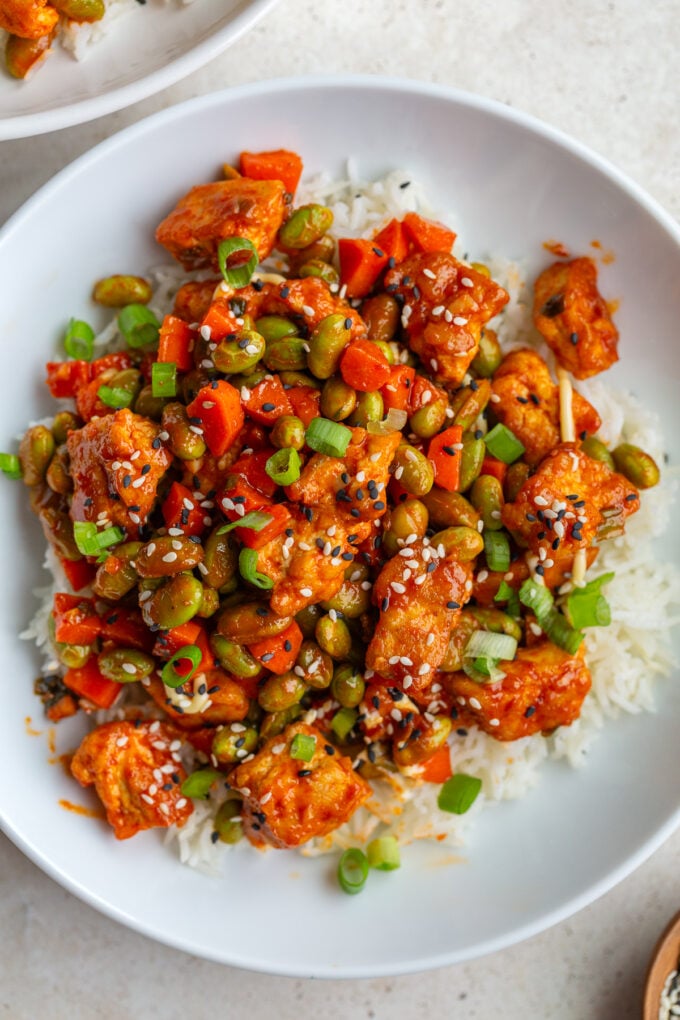 gochujang tofu and edamame stir fry in a large white bowl topped with sesame seeds