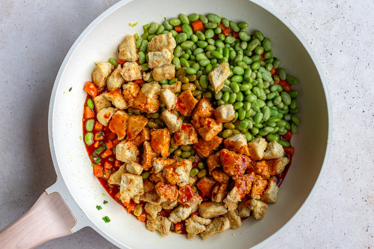 gochujang tofu in a skillet with tofu and edamame on top