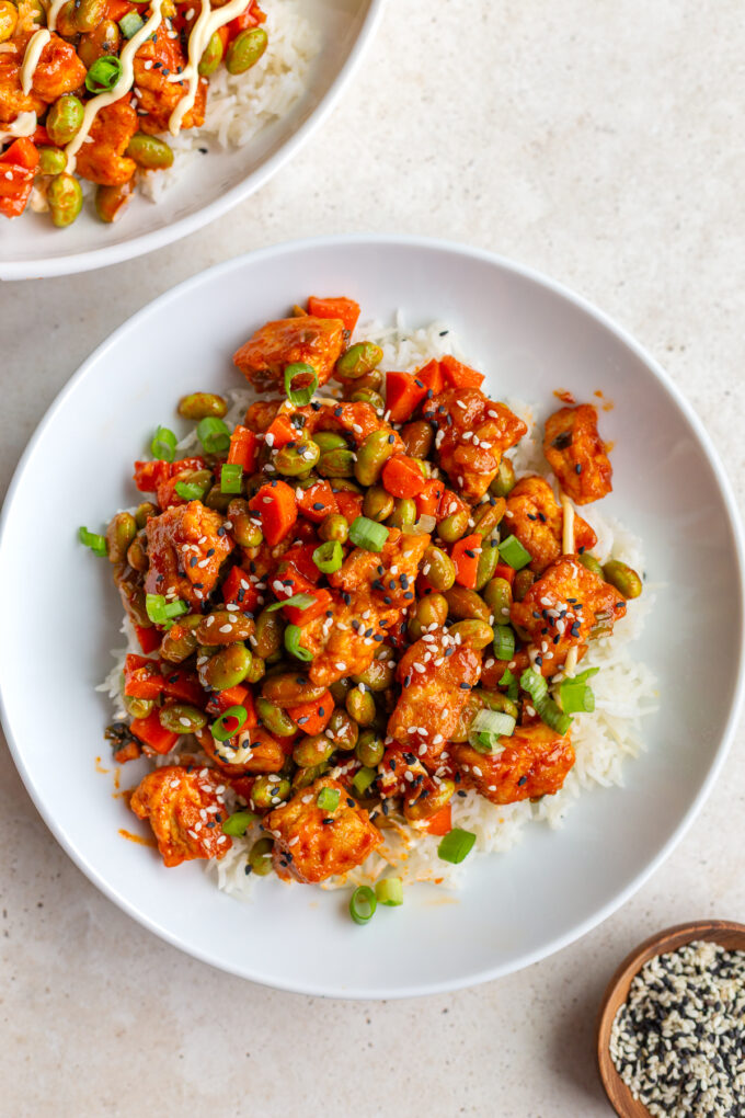 gochujang tofu and edamame stir fry in a large white bowl topped with sesame seeds
