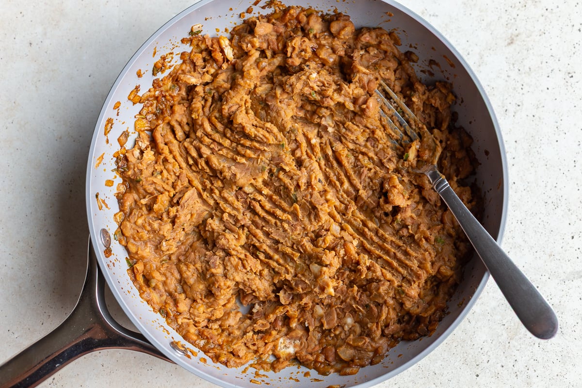 how to make this refried beans recipe: add in the cooked pinto beans and mash them