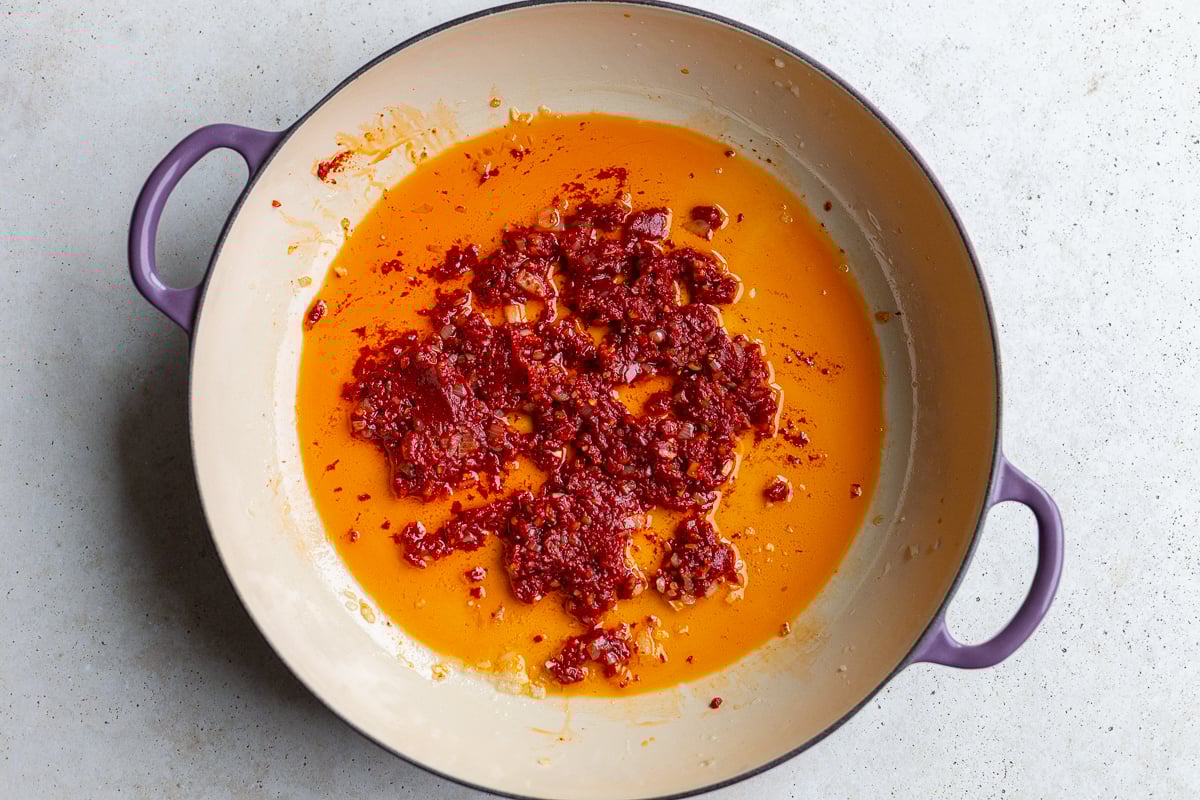 how to make creamy butter beans - step 2 is oil heat in a skillet with sauteed shallot and garlic with tomato paste mixed in