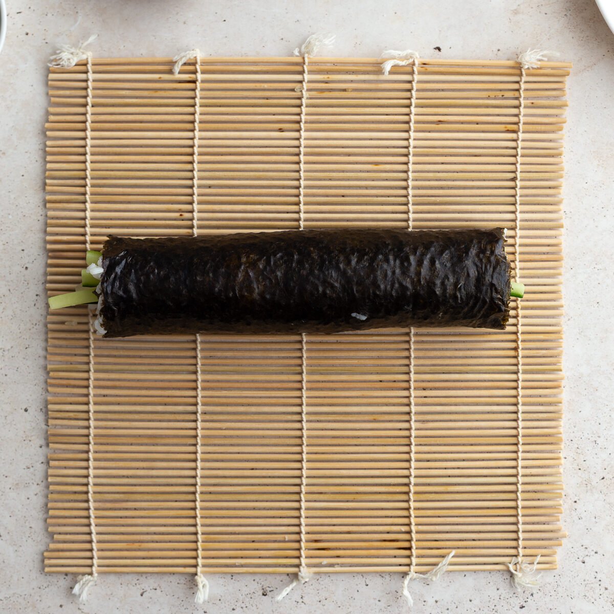 Sushi roll rolled up on a sushi mat.