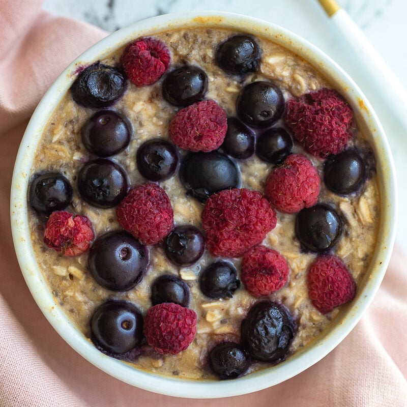 single serve baked protein oats in a ramekin and topped with fruit.