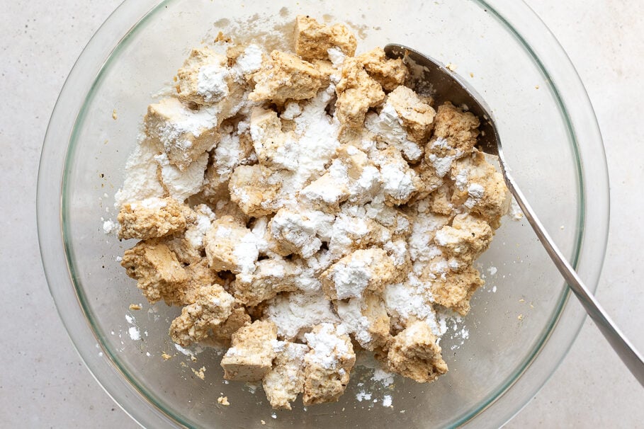 tofu torn into chunks placed in a large bowl tossed with soy sauce and cornstarch