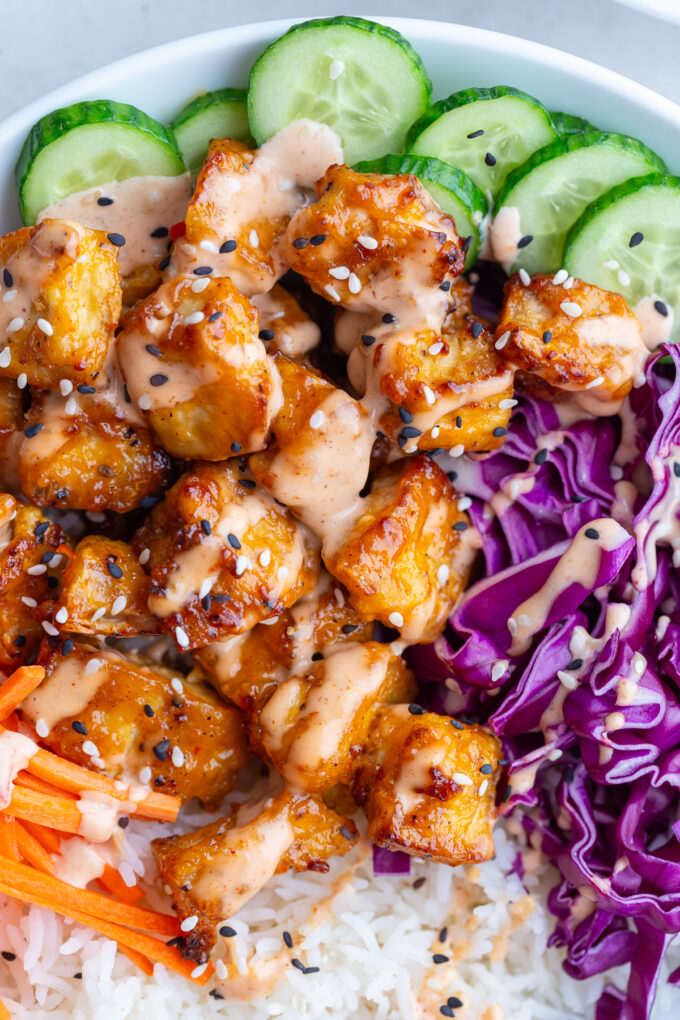 bang bang tofu bowls with rice, cucumber, red cabbage, and carrot sticks