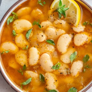 brothy beans in a large bowl with lemon and fresh herbs
