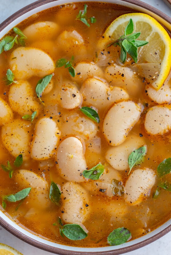 brothy beans in a large bowl with lemon and fresh herbs