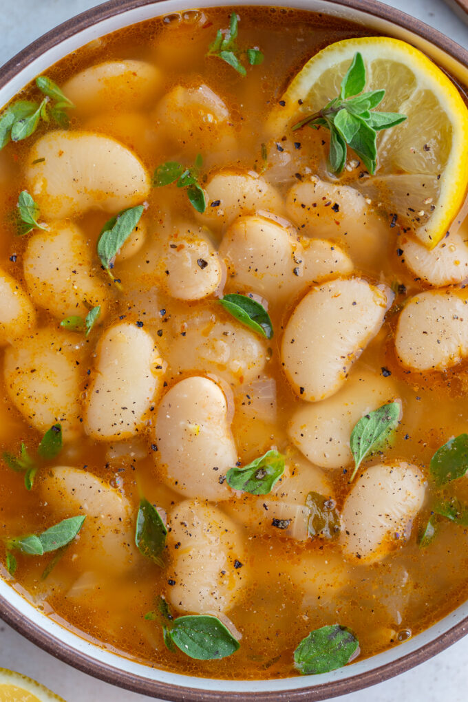 brothy beans in a large bowl with lemon and fresh herbs