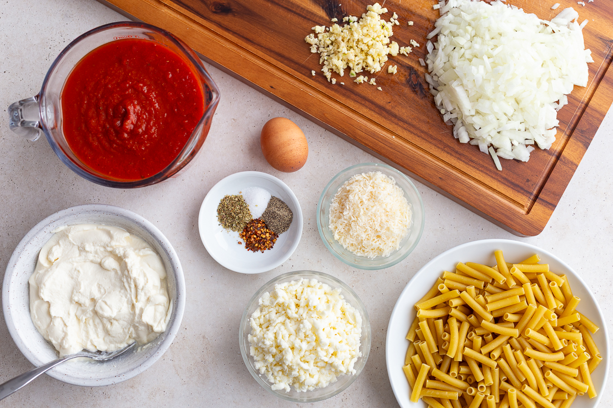ingredients need to make vegetarian baked ziti recipe including marinara, cheese, ziti pasta, egg, spices, and ricotta and onion and garlic