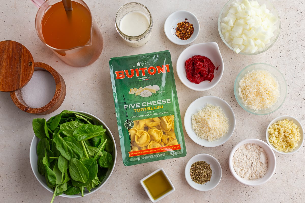 ingredients needed to make tortellini soup including cheese tortellini, tomato paste, spinach, broth, cream, cheese, and spices