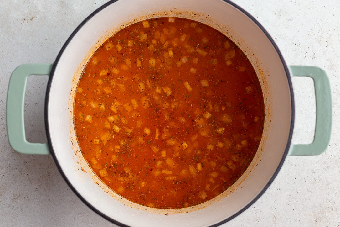 broth in a large pot with onion floating in it