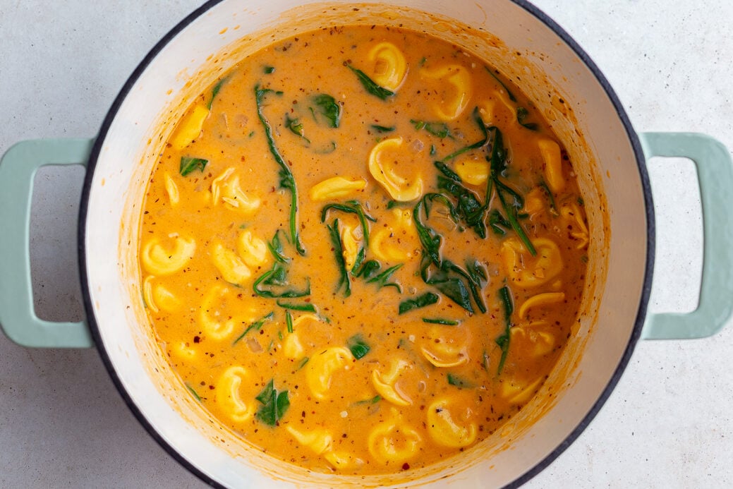 creamy tortellini soup in a large pot where you can see the tortellini and spinach floating at the top