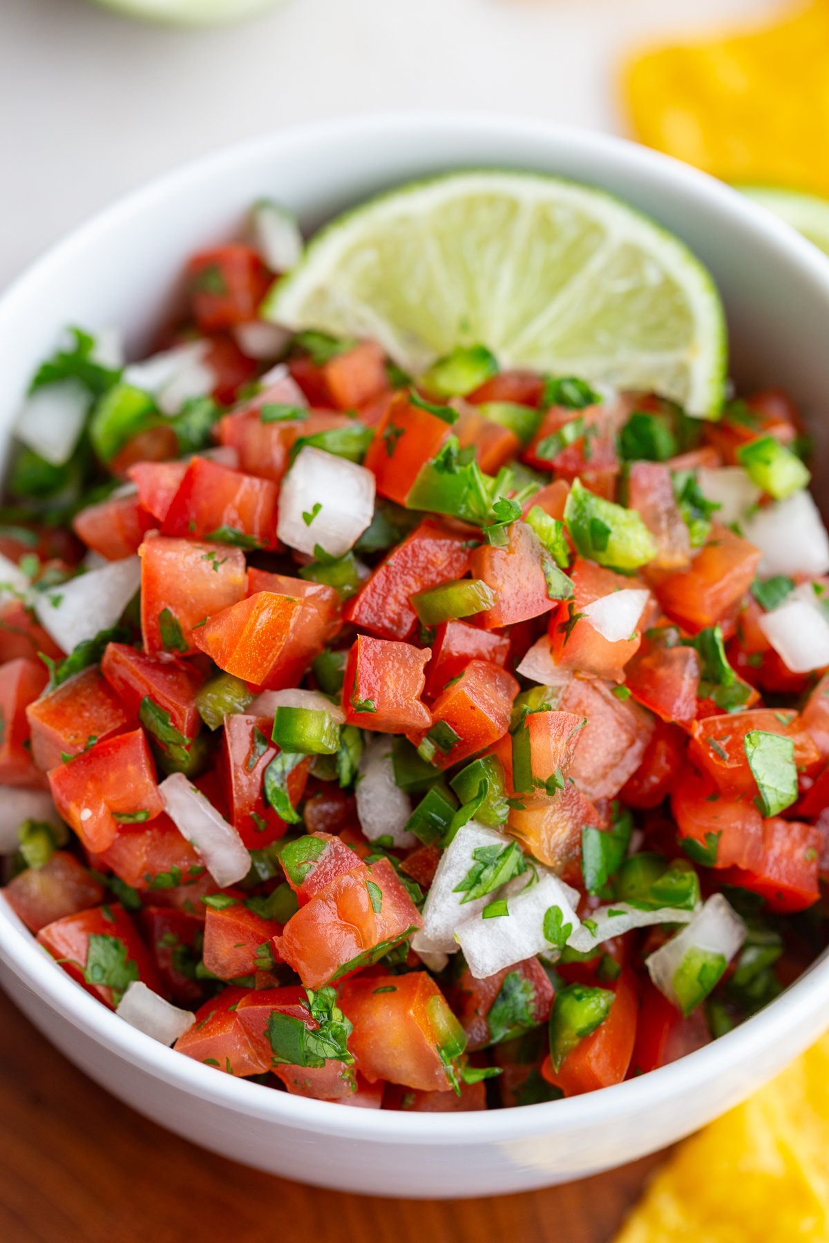 pico de gallo in a white bowl with 2 limes on top