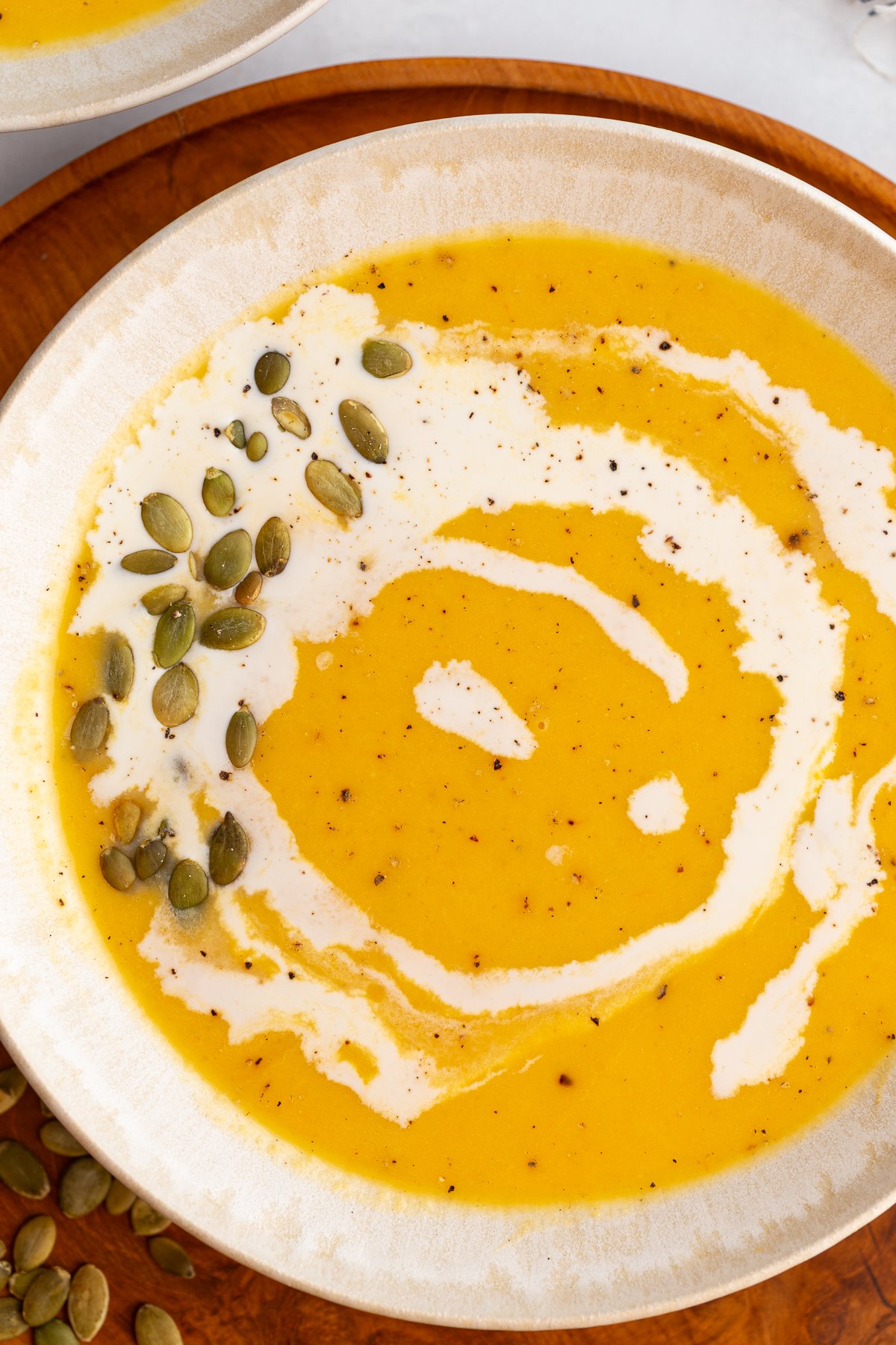 Creamy Roasted Butternut Squash Soup in a large bowl drizzled with cream and pepitas