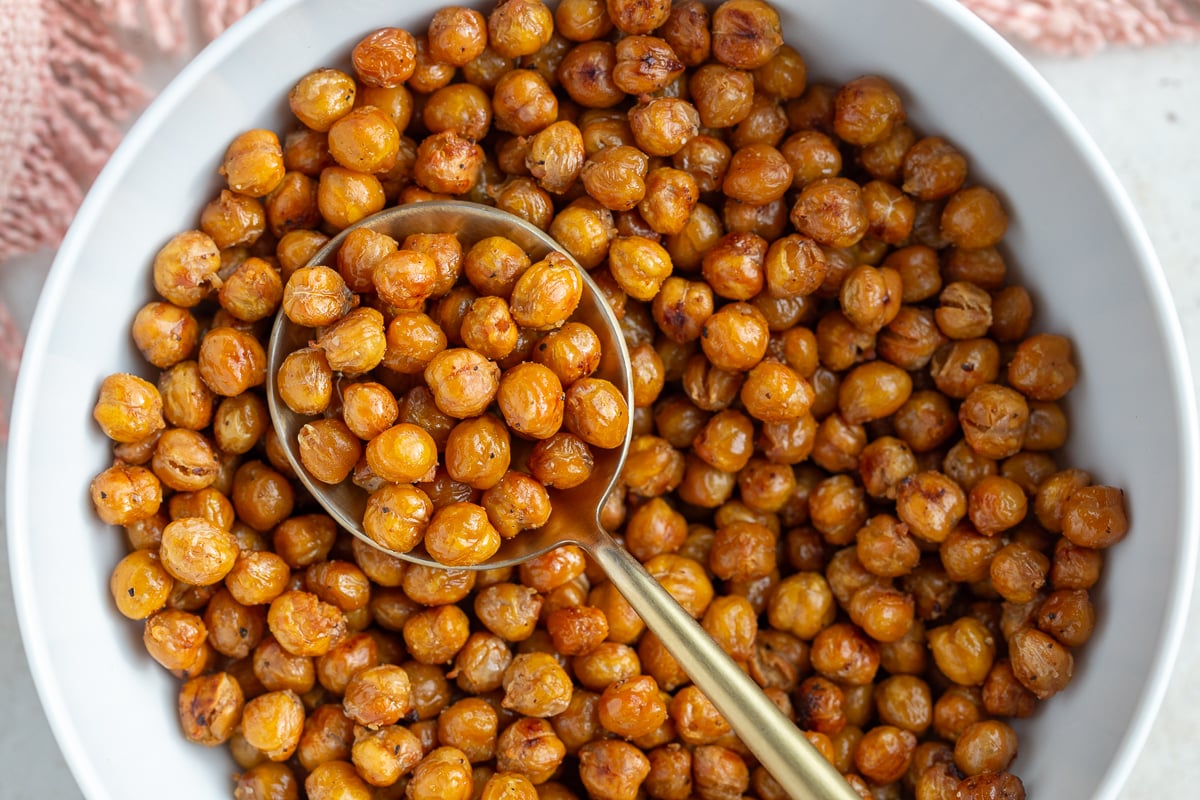 crispy roasted chickpeas in a large white bowl with a big gold spoon in the bowl
