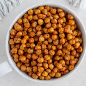 crispy roasted chickpeas in a large white bowl with a big gold spoon in the bowl