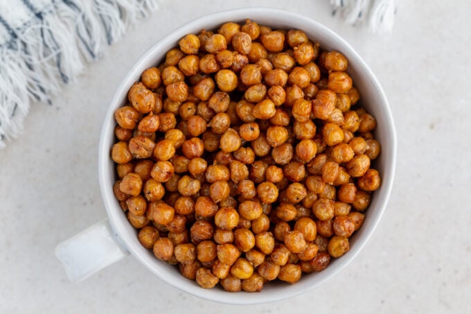 crispy roasted chickpeas in a large white bowl with a big gold spoon in the bowl