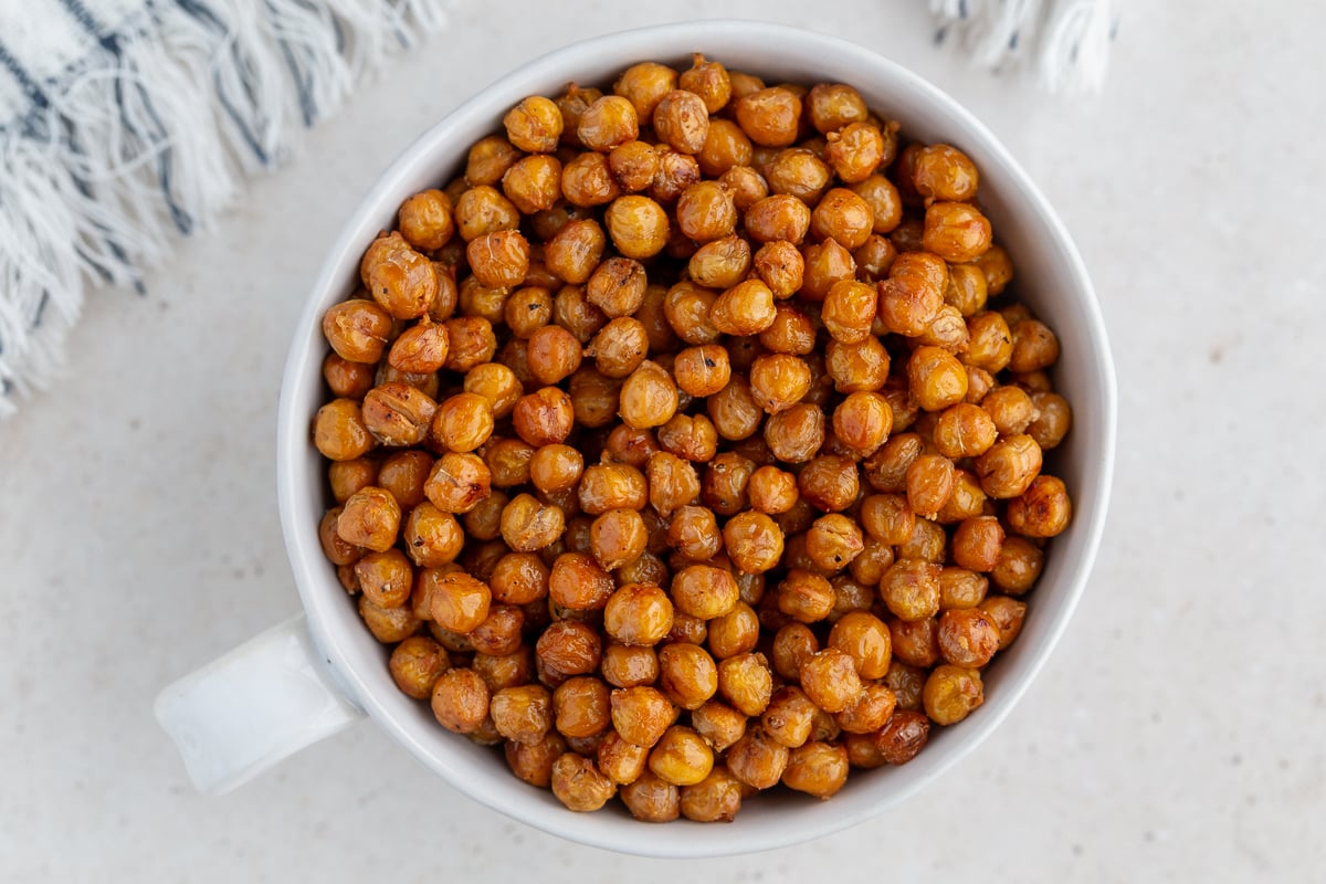 crispy roasted chickpeas in a large white bowl with a big gold spoon in the bowl