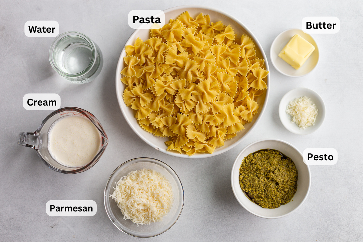ingredients needed to make creamy pesto pasta including pesto, pasta, parmesan, water and cream