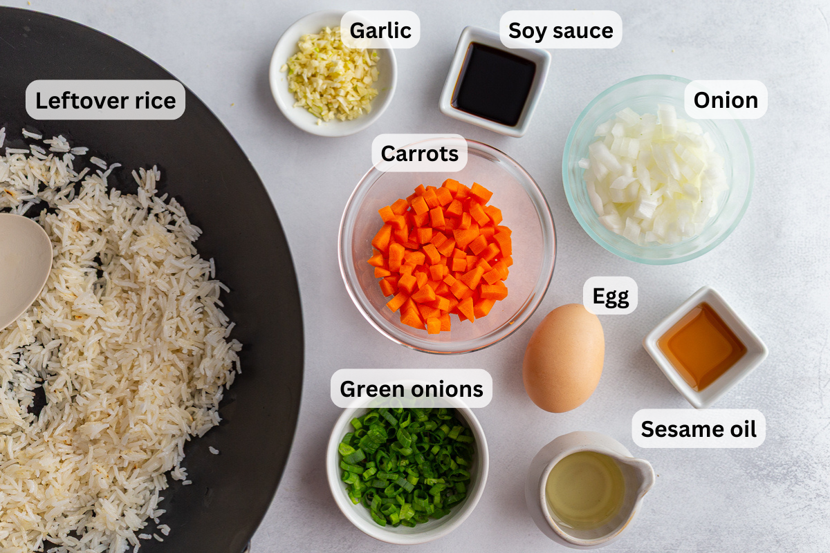 ingredients needed to make veggie fried rice including leftover white rice, carrots, green onion, garlic, oil, and soy sauce