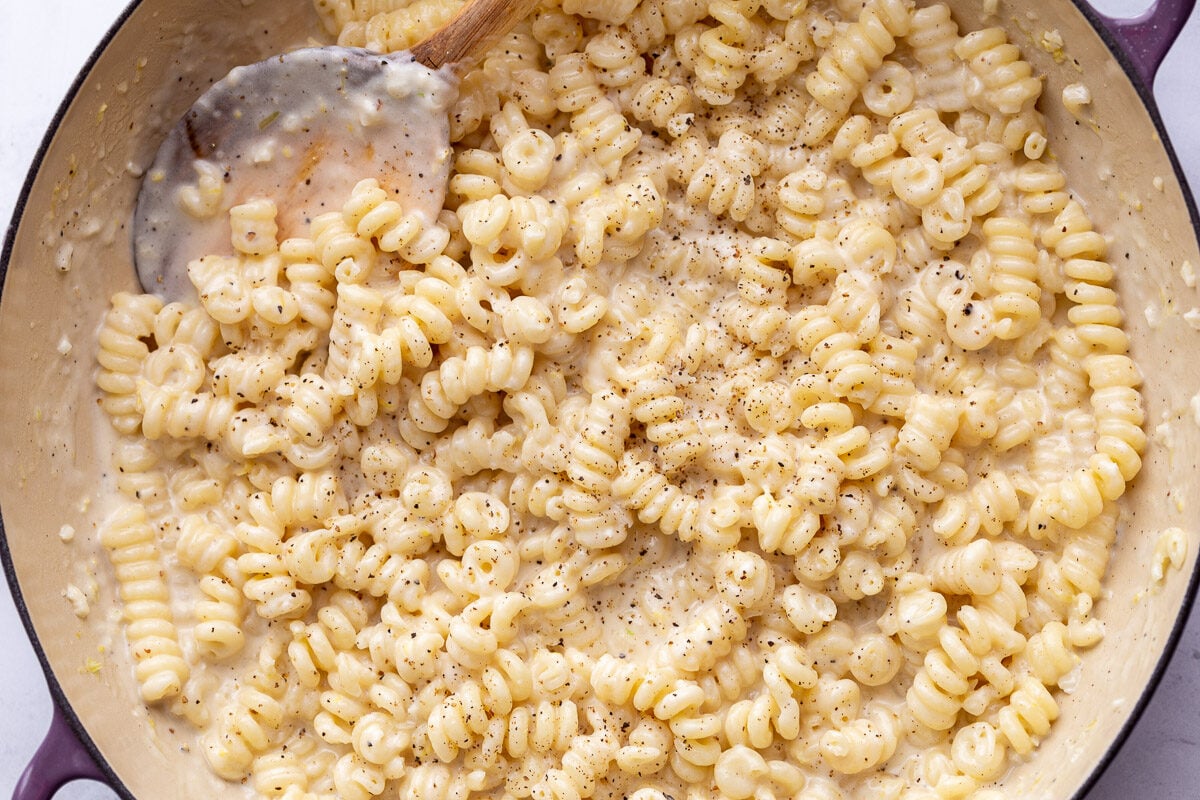 Stirring creamy noodles in a large pan.