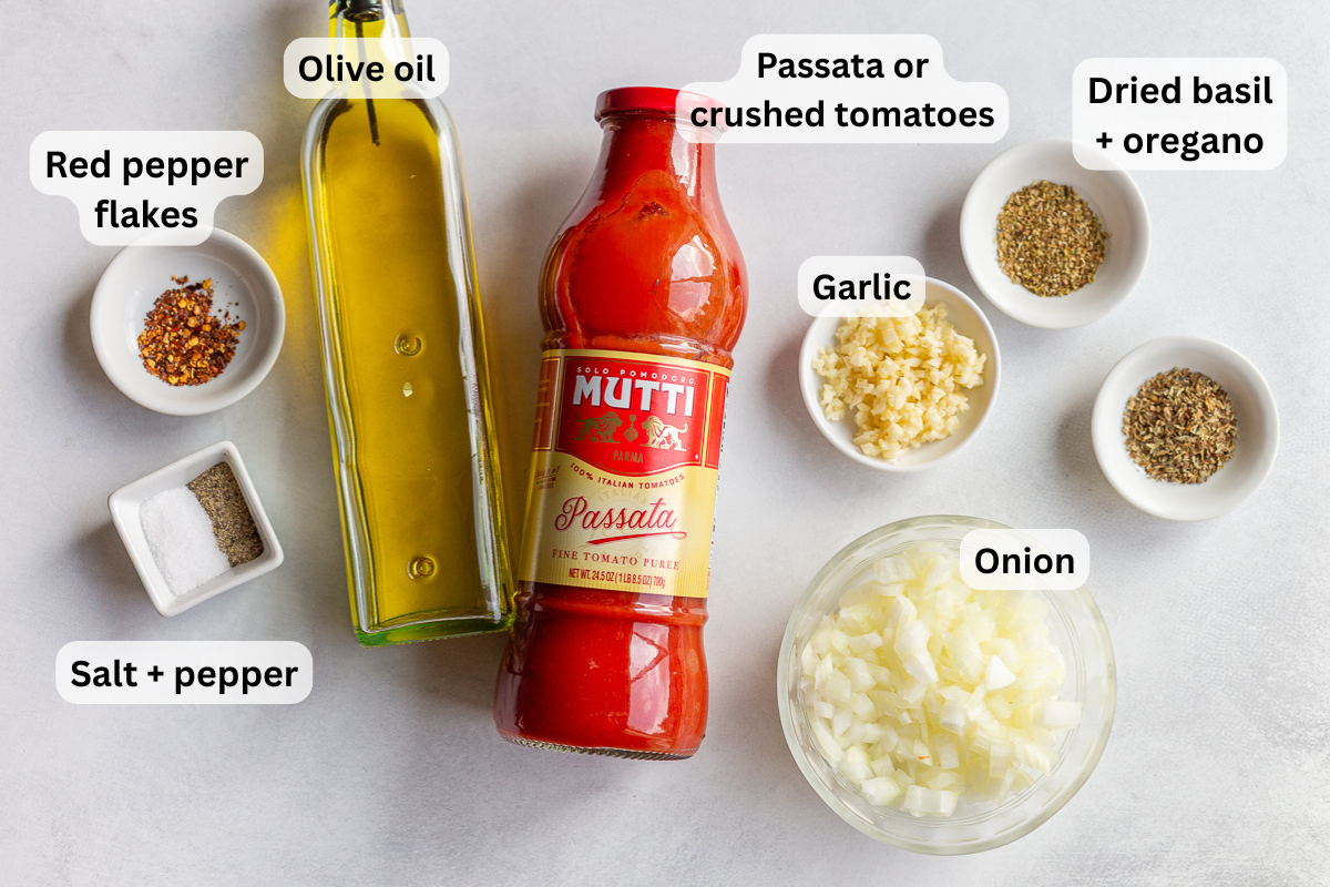 ingredients need to make homemade marinara sauce including passata, olive oil, spices, onion and garlic. ingredients are labeled on the image with black text