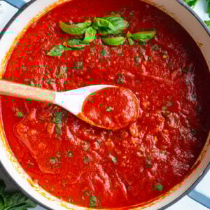quick marinara sauce in a large skillet. there's green basil on top and a spoon in the pot with some sauce scooped up