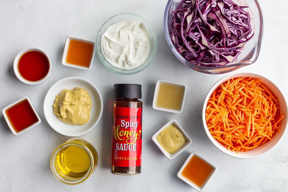 ingredients needed to make hot honey coleslaw including cabbage, carrots, and hot honey