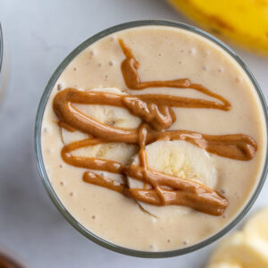 peanut butter banana smoothie from the top down with fresh slices of banana on top and a drizzle of peanut butter